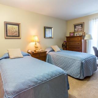 A cozy bedroom with twin beds, decorated in a classic style with soft lighting and elegant furniture.