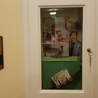 A door with a glass window featuring various posters and a distorted keyhole.