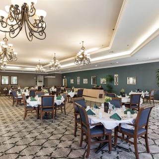 A spacious and elegantly designed dining room with chandelier lighting and meticulously arranged tables, creating a sophisticated atmosphere.