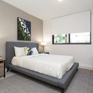 A modern, minimalist bedroom with a gray bed frame and simple decor.