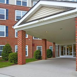 A brick building entrance with a covered walkway supported by pillars.
