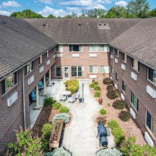 Aerial view of a courtyard in a brick apartment complex, featuring landscaped gardens and outdoor seating.