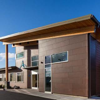 A modern building featuring wood accents and large windows under a clear blue sky.
