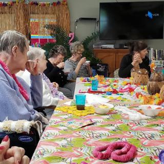 A vibrant community gathering with elderly individuals engaged in a creative activity around a decorated table.