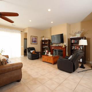 A cozy living room featuring a sofa, armchairs, and a coffee table, with bookshelves flanking a fireplace topped by a television.