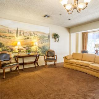 A cozy living room with a mural on the wall, featuring a sofa, chairs, and a chandelier.