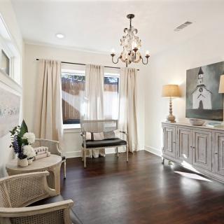 A cozy living room with elegant decor, featuring a chandelier, hardwood floors, and soft lighting.