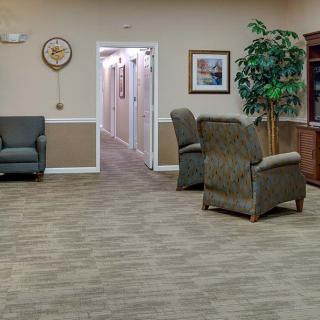 A cozy waiting room with armchairs, a clock, and decorative elements leading to a hallway.