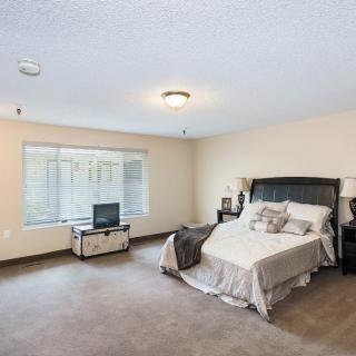 A spacious bedroom with minimalist decor, featuring a bed and side tables.