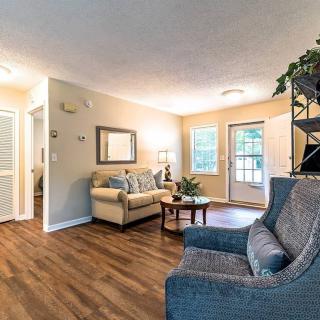 A cozy living room with a sofa, armchair, and wood flooring.
