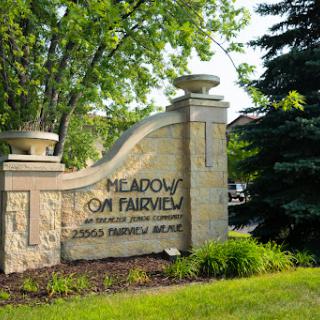 Entrance sign for Meadows on Fairview, surrounded by lush greenery.