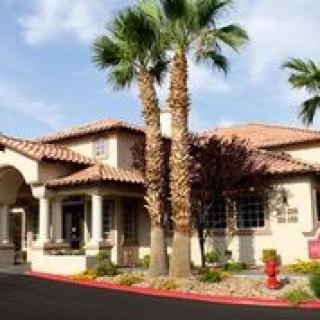 A large residential house with palm trees and a landscaped front yard.