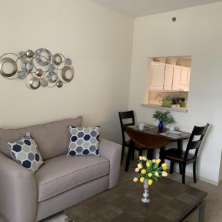 A cozy living room with a stylish sofa and decorative wall art, featuring a small dining area.