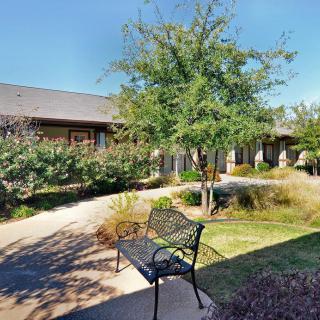 A peaceful courtyard with a bench and landscaped greenery in front of a building.