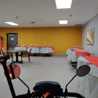 A spacious dining area with tables set with red tablecloths against a vibrant yellow wall.