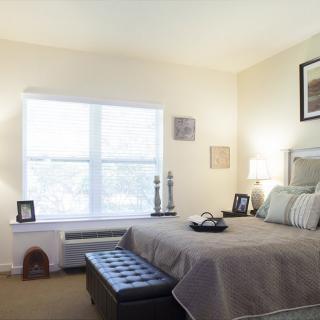 A well-lit bedroom with a neatly made bed and tasteful decor.