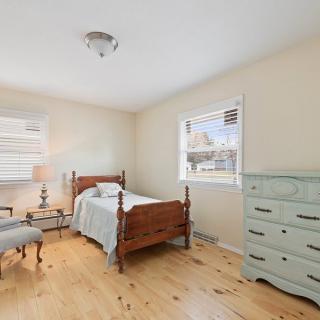 A cozy bedroom featuring a single bed with vintage furniture and abundant natural light.