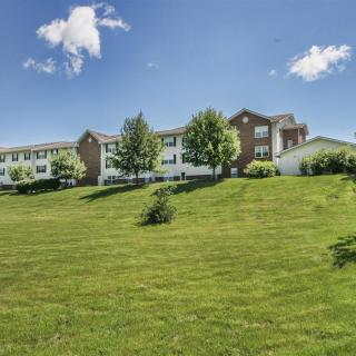 A building set against a backdrop of lush greenery and a clear blue sky with clouds.