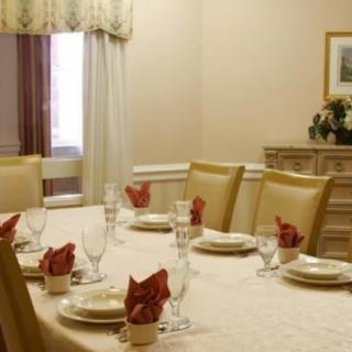 An elegantly set dining table with neatly arranged plates, glasses, and red napkins.