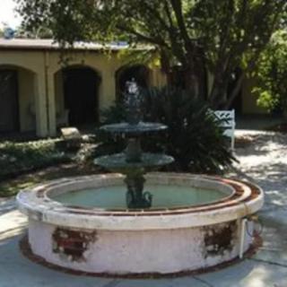 A tranquil courtyard featuring a decorative fountain surrounded by trees.