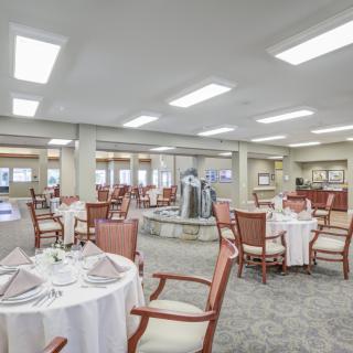 Elegant dining area with neatly arranged tables and chairs in a well-lit setting.