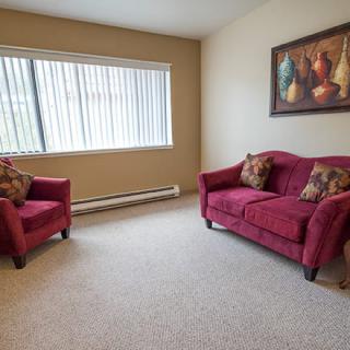 A cozy living room with red furniture and a large window.