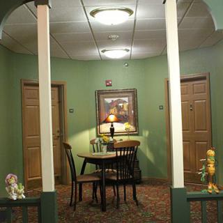 A cozy hallway with a small table and chairs, surrounded by doors and soft lighting.