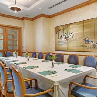 A well-appointed meeting room with a large table and chairs, adorned with elegant artwork on the wall.
