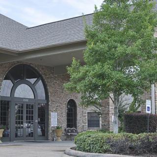 A brick building with an arched entrance surrounded by greenery.