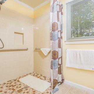 A bright bathroom with a shower area, featuring a patterned shower curtain and tiled floor.