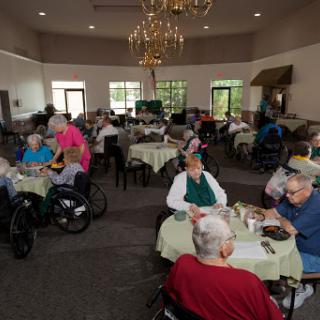 Residents enjoying a meal and socializing in a care home dining area.