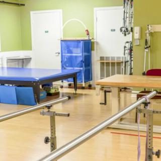 A physical therapy room equipped with exercise tables and parallel bars.