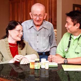A doctor discussing medication with an elderly patient and a family member at home.