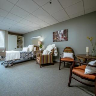 A comfortable and well-furnished hospital room with a single bed, chairs, and decor.