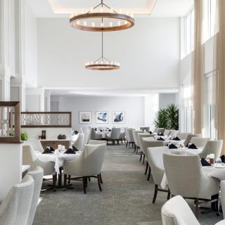 A spacious and modern restaurant interior with elegant chandeliers and comfortable seating.