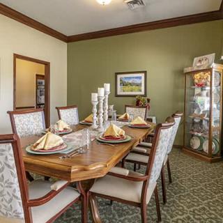 A well-decorated dining room with a wooden table and chairs, elegant place settings, candles, and framed artwork on the wall.