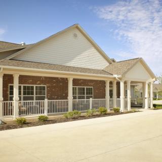 A single-story brick residential house with a porch under a clear blue sky.