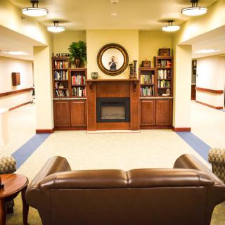 A cozy living room featuring a fireplace and bookshelves, with comfortable seating arrangements.
