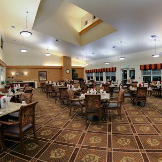 A spacious dining area set up with neatly arranged tables and chairs, illuminated by soft lighting.