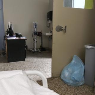 A view from a hospital room, displaying the door and medical equipment in the adjacent area.