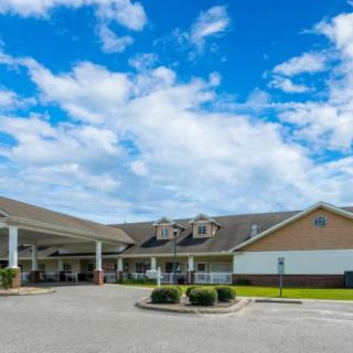 A large residential building with a driveway under a partly cloudy sky.