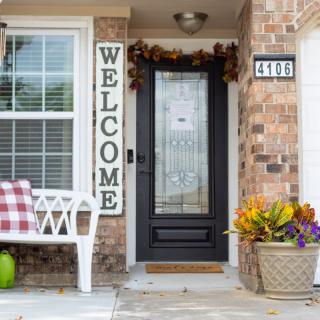 A cozy front porch with a welcome sign, decorated for fall.