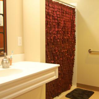 A bathroom featuring a red shower curtain and a white sink with a mirror.