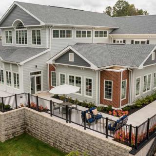 A modern two-story house with a spacious patio and landscaped surroundings.