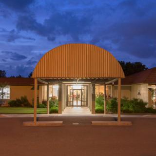 A warmly lit building entrance at night with a curved canopy.