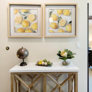 A stylish console table decorated with lemon-themed artwork, a globe, and fresh flowers.