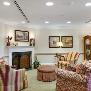 A cozy living room featuring armchairs, a fireplace, and artwork on the walls.