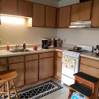 A cozy kitchen featuring wooden cabinets, a stove, and essentials for cooking.