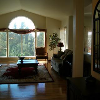 A cozy living room featuring a large arched window that lets in ample natural light, complemented by hardwood floors and comfortable seating.