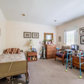 A cozy bedroom with a hospital bed and a walker, featuring homey decor and furniture.